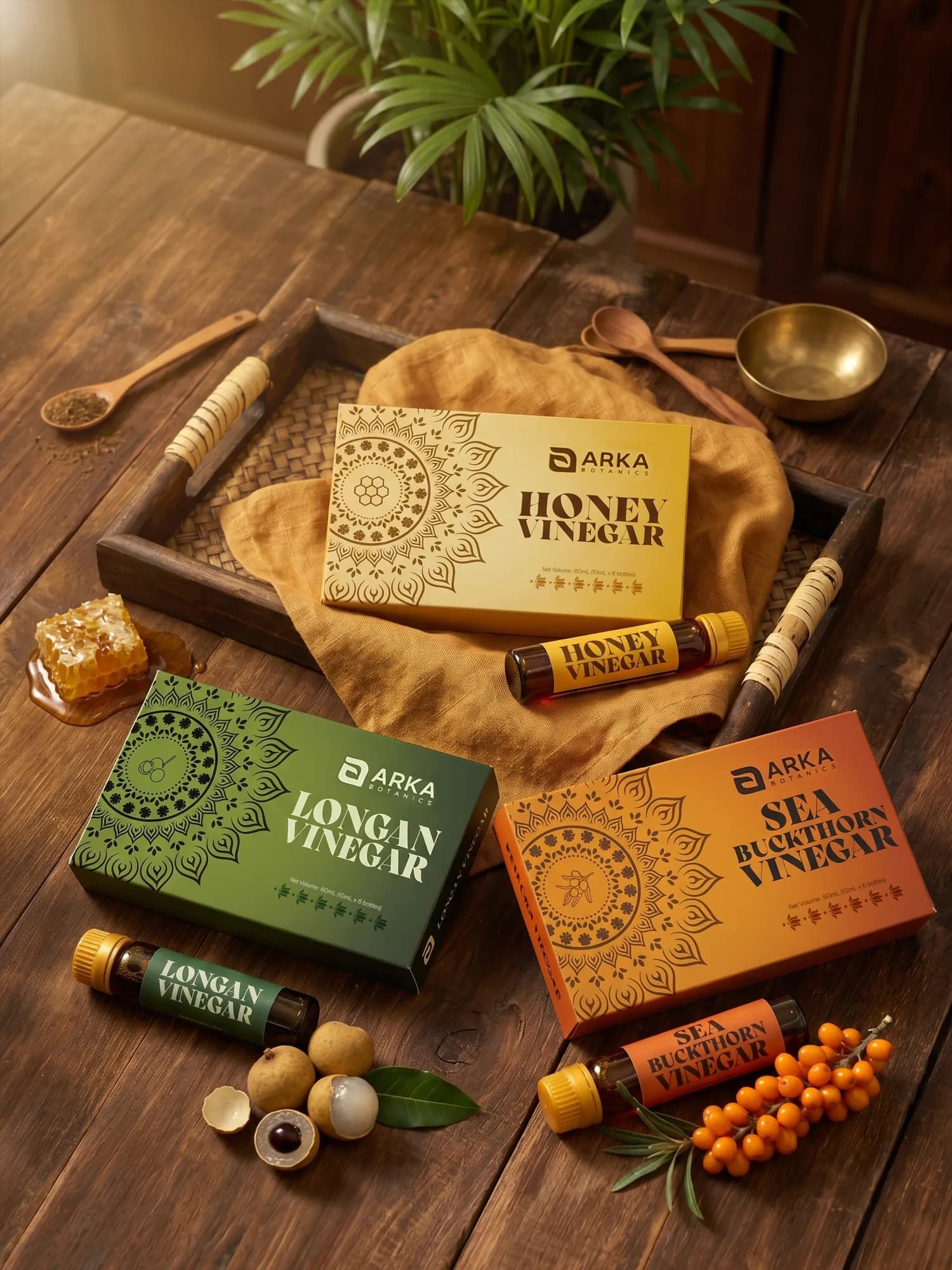 The Arka Botanics range — Honey, Longan and Sea Buckthorn vinegars on a wooden table with botanicals